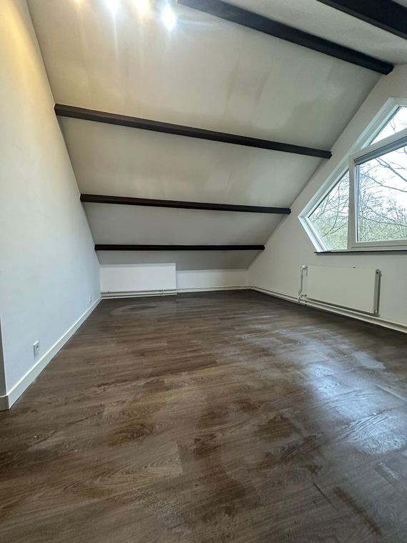 Afgewerkte zolderkamer met zichtbare balken en nieuwe vloer